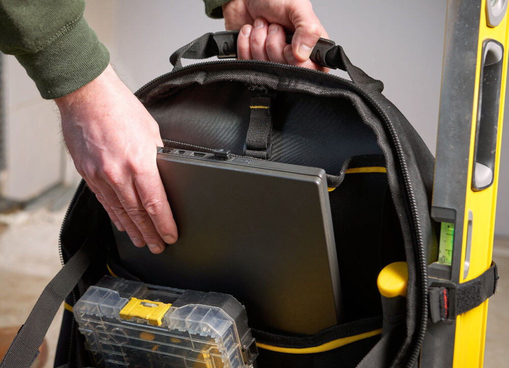 Plecak monterski STANLEY Fatmax 1-95-611 pomieszczenie otwarty plecak osoba wyciąga z plecaka laptopa specjalna usztywniona kieszeń do przenoszenia laptopa tabletu lub elektronarzędzi miękka wyściółka ochrona przed uderzeniami wstrząsami i zarysowaniami bezpieczeństwo