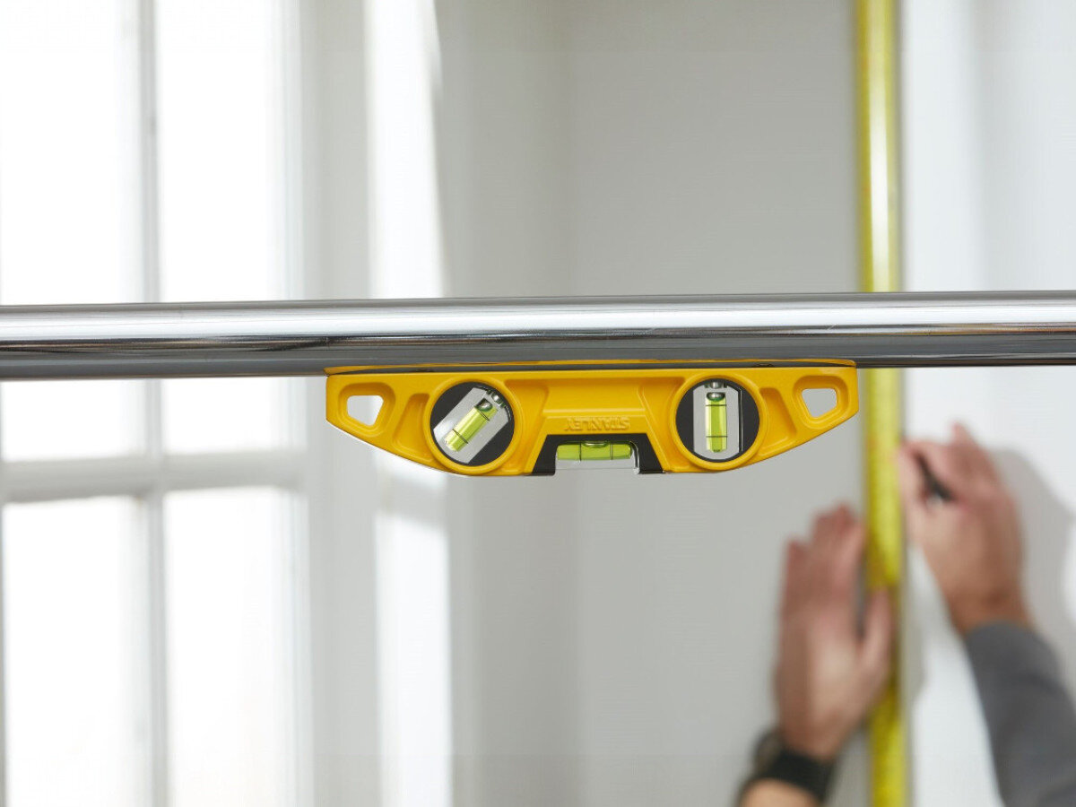 Poziomnica ręczna STANLEY Fatmax 0-43-603, poziom, budowa, pion, magnesy, poziomica przytwierdzona do rury nad sufitem, sprawdzająca poziom