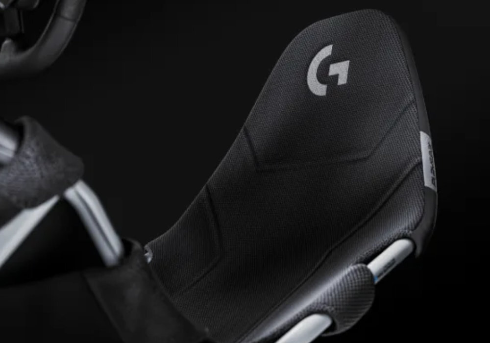 Czarny fotel gamingowy z widocznym logo \'G\' na oparciu oraz teksturą materiału. Na boku znajduje się mała metka z napisem \'PLAYSEAT\'.