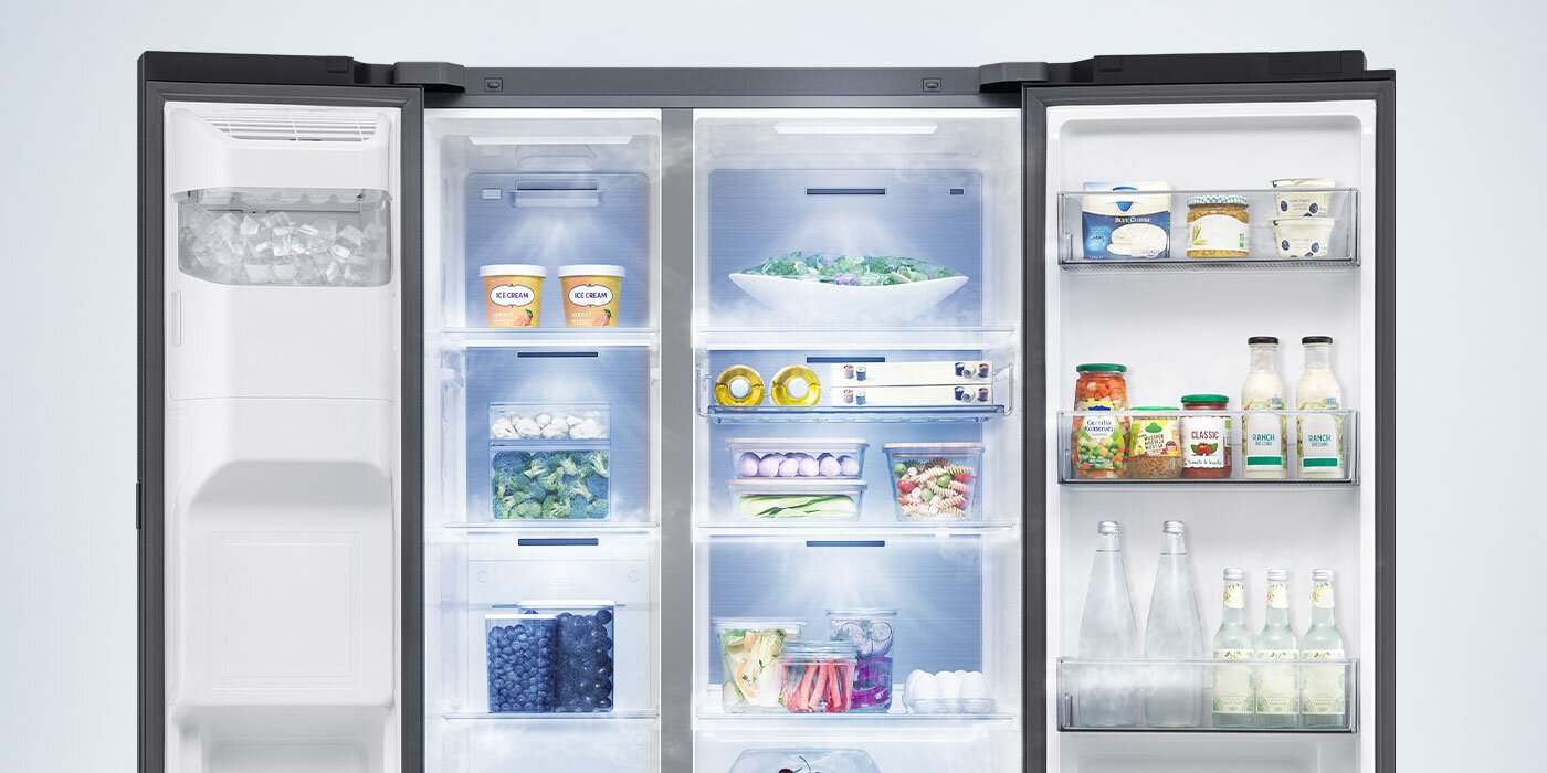 system all around cooling w lodówkce side by side rs90f64eefeo Wnętrze lodówki z otwartymi drzwiami, wypełnione różnorodnymi produktami spożywczymi, takimi jak warzywa, napoje i pojemniki z jedzeniem. Po lewej stronie widoczna jest kostkarka do lodu.