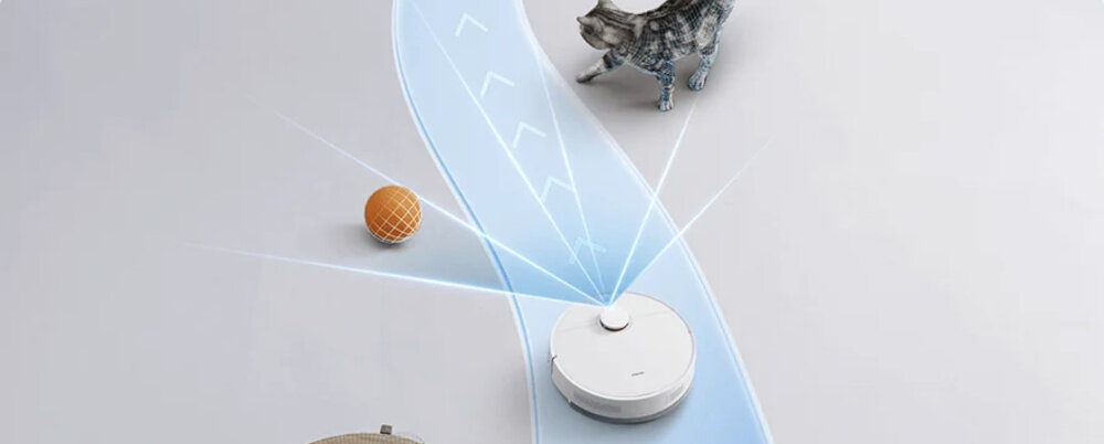 Na obrazie widoczny jest biały robot sprzątający na podłodze, emitujący niebieskie linie symbolizujące jego trasę. Obok znajdują się piłka i kot.