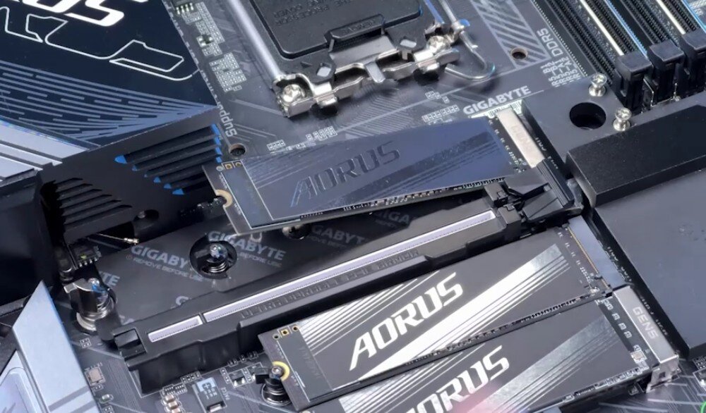 Na obrazie widoczna jest płyta główna z logo GIGABYTE i AORUS, z zamontowanymi modułami pamięci. W tle widać złącza i elementy elektroniczne.