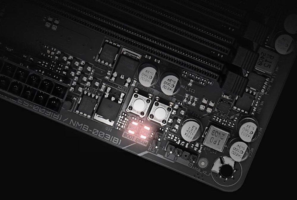 Zbliżenie na fragment płyty głównej z widocznymi elementami elektronicznymi i dwoma podświetlonymi przyciskami. Na płycie widoczny jest tekst: \'BOOT DRAM\'.
