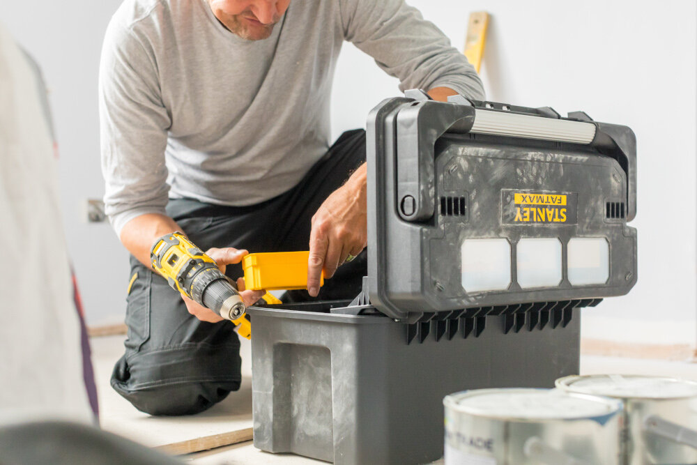Skrzynia na narzędzia STANLEY Fatmax Pro Cantilever FMST1-75792 pomieszczenie otwarta skrzynka widoczna od tyłu obok osoba z narzędziami w dłoniach obudowa z tworzywa sztucznego odporna na uszkodzenia mechaniczne i działanie czynników zewnętrznych metalowy zatrzask zawiasy z wysokiej jakości tworzywa sztucznego trwałość i pewne zamykanie udźwig do 25 kg