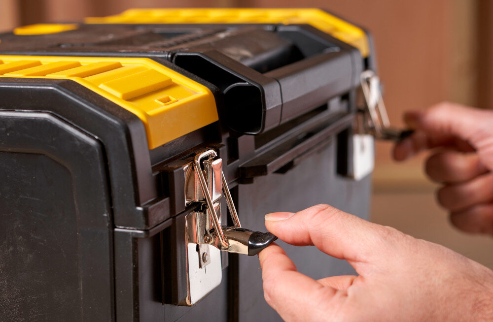 Skrzynka narzędziowa STANLEY 1-70-326 zbliżenie na zatrzaski osoba trzyma zatrzaski w dłoniach metalowe zatrzaski łączące poszczególne segmenty zawiasy z tworzywa sztucznego płynne otwieranie i zamykanie