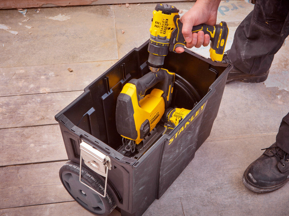 Skrzynka narzędziowa STANLEY 1-70-326 pomieszczenie dolna skrzynka ustawiona a na podłodze osoba wyciąga z wnętrza wiertarkę pojemność do 43,45 l drobne elementy ciężkie elektronarzędzia