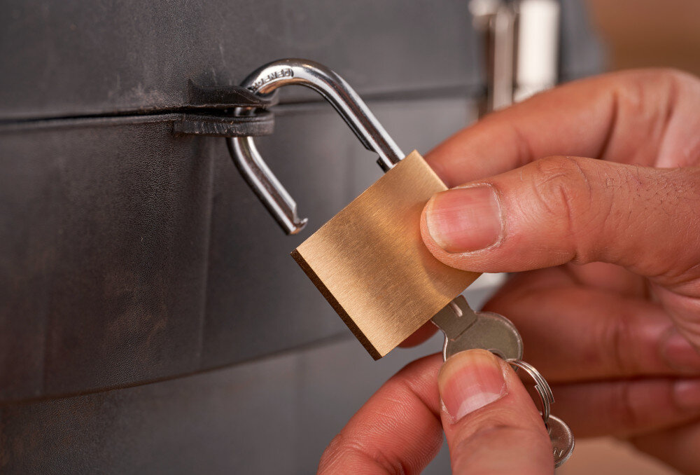 Skrzynka narzędziowa STANLEY 1-93-968 zbliżenie na otwór do montażu kłódki osoba zakłada kłódkę na skrzynkę możliwość zamknięcia na kłódkę bezpieczeństwo przechowywanych narzędzi cenne akcesoria są dobrze chronione