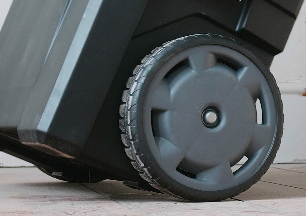 Skrzynka narzędziowa STANLEY 1-93-968 pomieszczenie zbliżenie na koło drewniana podłoga wytrzymałe kółka transportowe teleskopowy uchwyt łatwe przemieszczanie zestawu wychylany uchwyt stabilność podczas prowadzenia kształt ogranicza zmęczenie dłoni