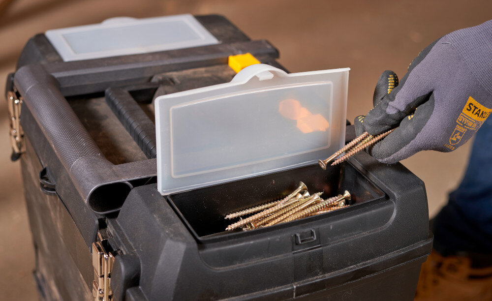 Skrzynka narzędziowa STANLEY 1-93-968 pomieszczenie zbliżenie na pokrywę górnej skrzynki zbliżenie na organizery osoba wyciąga z wnętrza akcesoria w górnej części dwa przezroczyste organizery wygodne przechowywanie drobnych akcesoriów oddzielne przegródki porządek praktyczne rozwiązanie