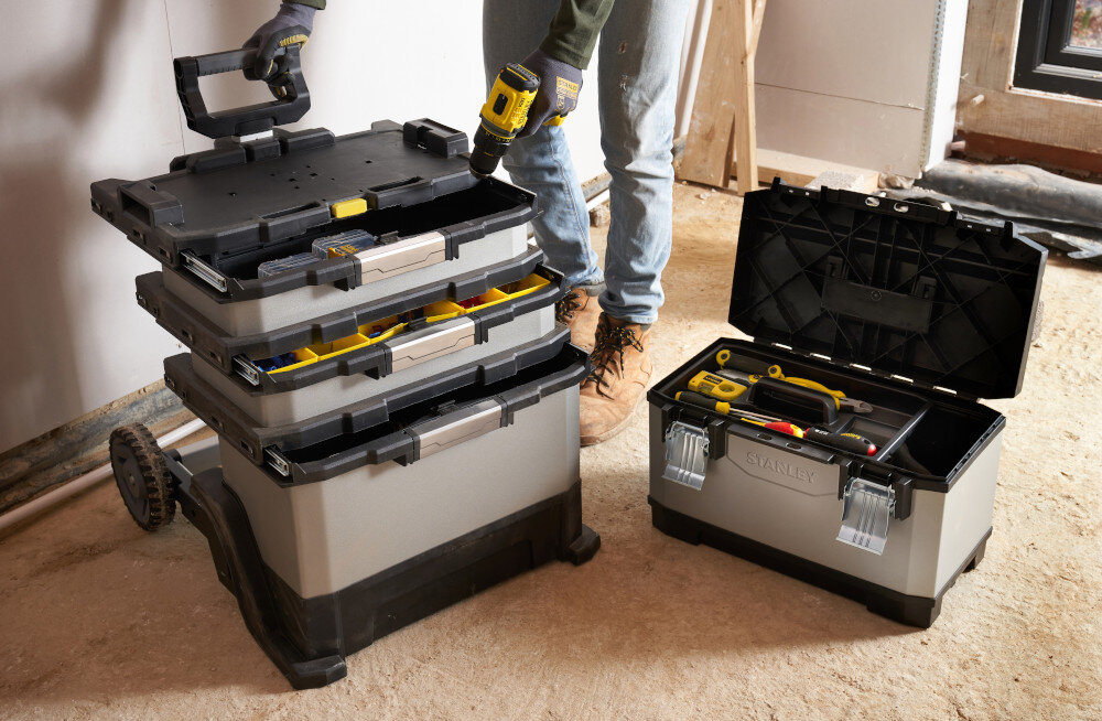 Skrzynka narzędziowa STANLEY FatMax 1-95-622 pomieszczenie skrznki ustawione na podłodze osoba wyciąga z wnętrza narzędzia składa się z czterech elementów odpinana skrzynia z tacką wewnętrzny organizer pionowy 20-calowy dwie głębokie szuflady duży pojemnik na ciężkie narzędzia można użytkować osobno