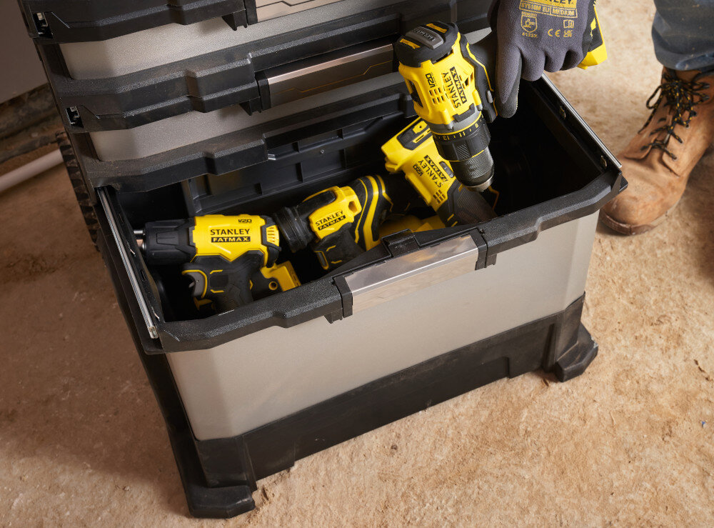 Skrzynka narzędziowa STANLEY FatMax 1-95-622 zbliżenie na dolny moduł krzynka na podłodze osoba wyciąga z wnętrza narzędzie do przechowywania większych i cięższych narzędzi metalowa konstrukcja sprawny transport otwarta forma