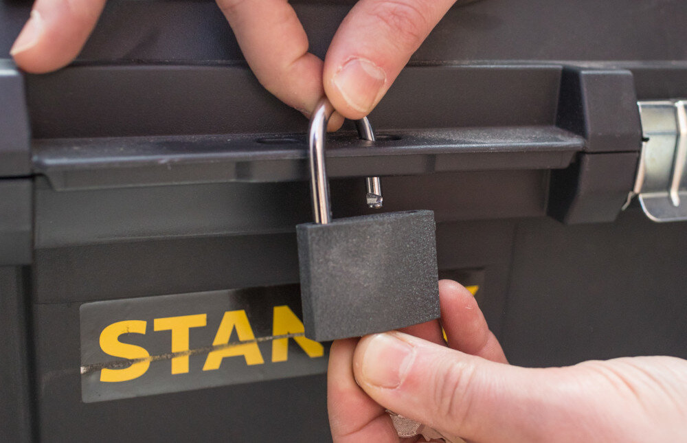 Skrzynka narzędziowa STANLEY STST1-80150 zbliżenie na otwór do kłódki osoba trzyma w dłoniach kłódkę otwór umożliwiający założenie kłódki bezpieczeństwo ochrona przed dostępem osób trzecich