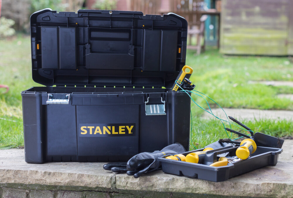 Skrzynka narzędziowa STANLEY Essential STST1-75521 skrzynka i tacka ustawioe na kamiennym podeście w tle trawa domek drewniany praktyczny gadżet pomaga uporządkować narzędzia akcesoria i drobne elementy montażowe efektywność codziennej pracy porządek