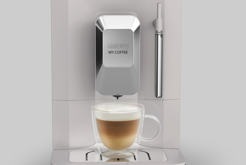 Ekspres do kawy w kolorze beżowym z napisem \'KRUPS MY COFFEE\' na przednim panelu. Przed ekspresem znajduje się filiżanka z kawą z mleczną pianką.