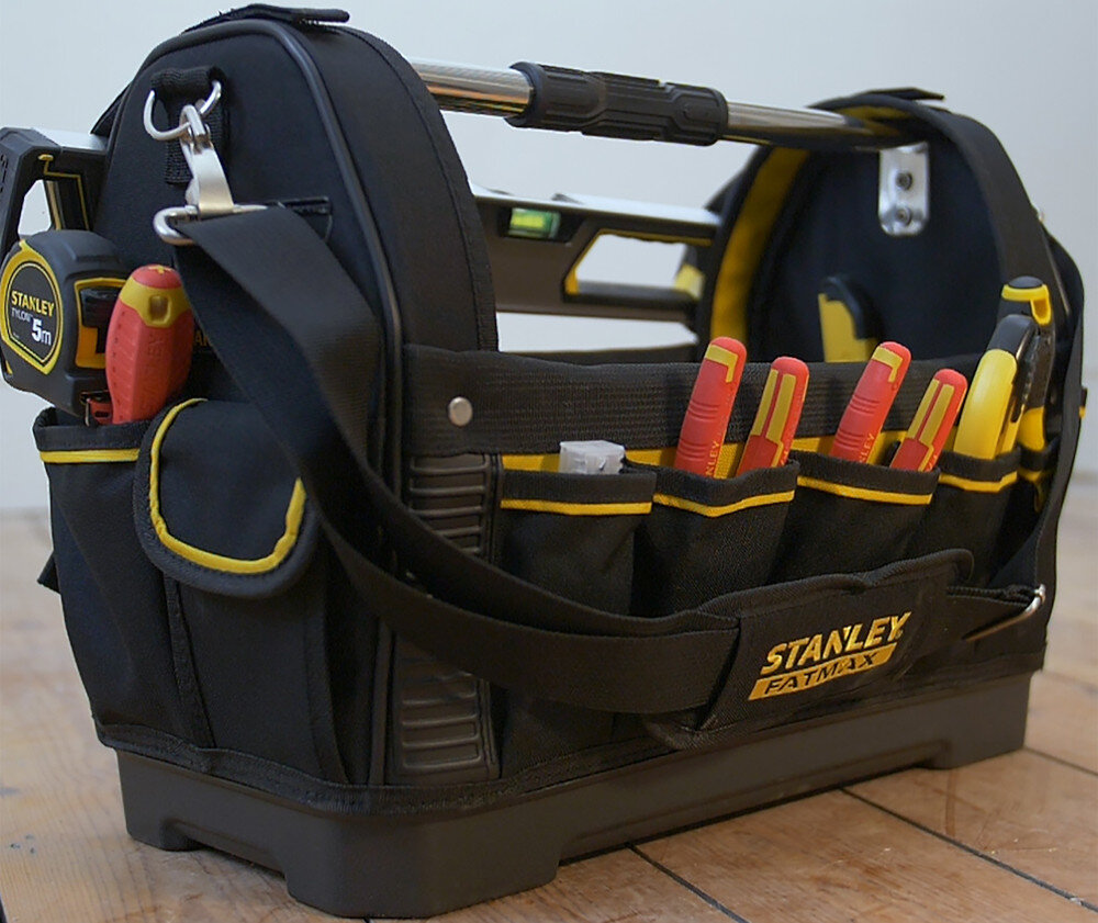 Torba narzędziowa STANLEY Fatmax 1-93-951 pomieszczenie drewniana podłoga torba wypełniona narzędziami w tle jasna ściana organizacja pracy porządek wśród narzędzi
