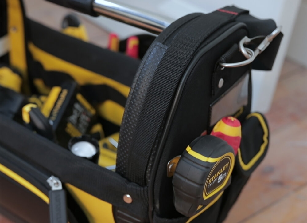Torba narzędziowa STANLEY Fatmax 1-93-951 pomieszczenie drewniana podłoga zbliżenie na bok i wnętrze torby wnętrze wypełnione narzędziami z mocnego nylonu 600x600 Denier ochrona przed przetarciami i uszkodzeniami wzmocnione szwy i panele nitowana konstrukcja