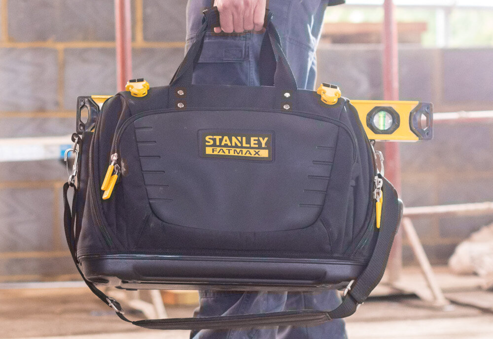 Torba narzędziowa STANLEY FMST1-80147 pomieszczenie osoba niesie torbę w dłoni w tle betonowa ściana funkcjonalne przechowywanie organizacja i wygoda w pracy