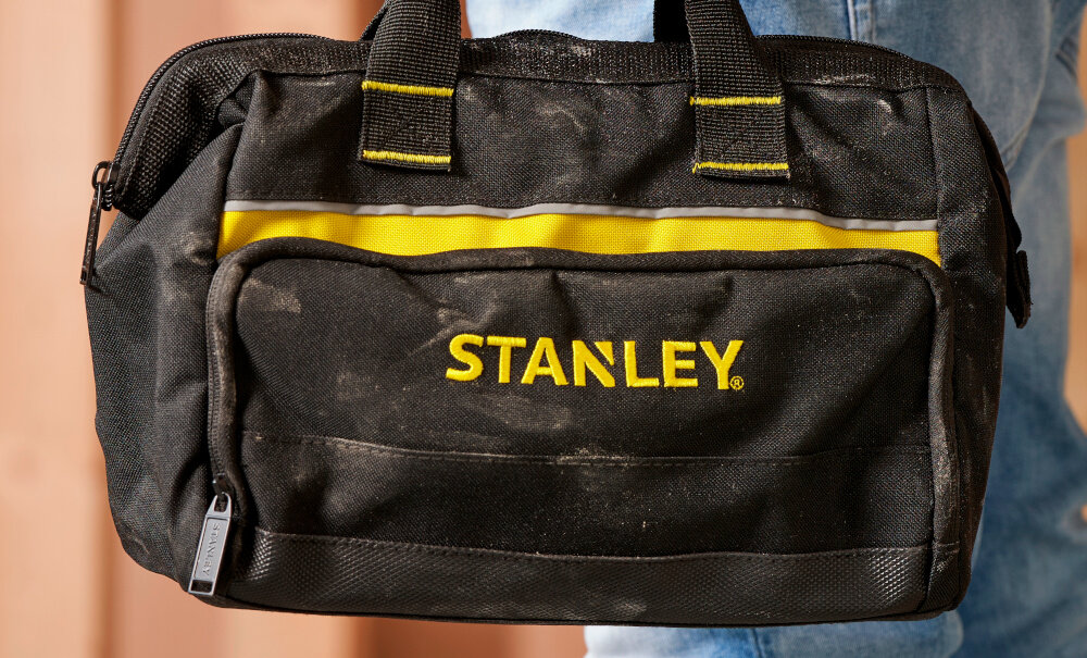 Torba narzędziowa STANLEY 1-93-330 pomieszczenie torba na tle ściany zamazane tło porządek mobilność ułatwia organizację codziennych zadań oszczędność czasu i energii