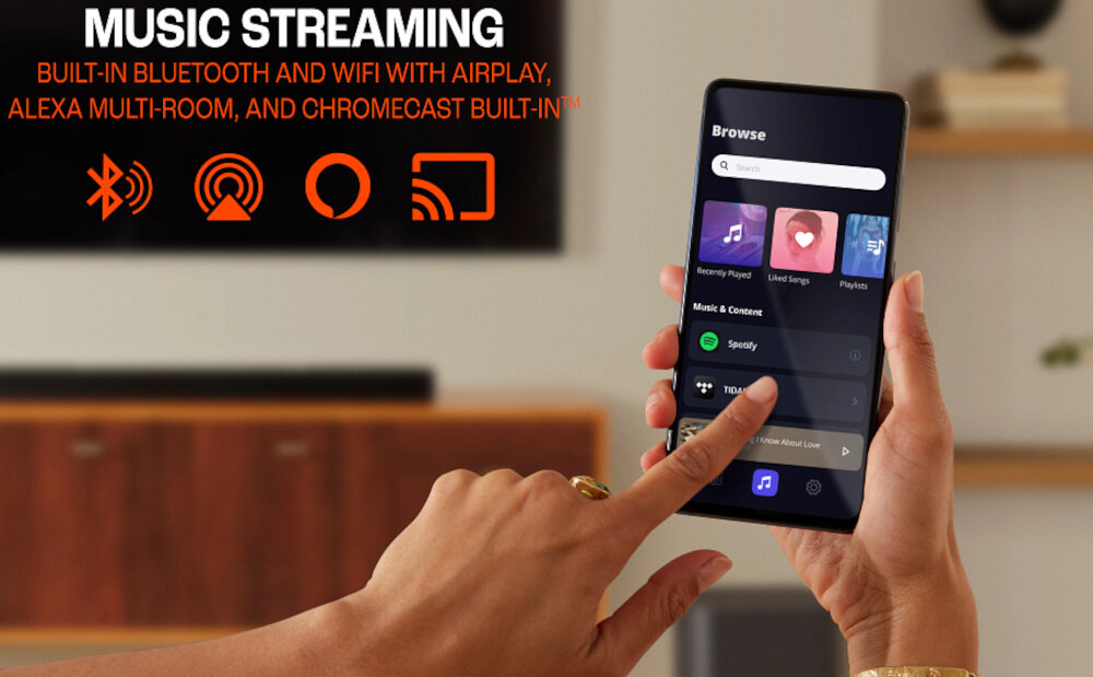 Osoba trzyma smartfon z aplikacją muzyczną, na ekranie widoczne są ikony Spotify i TIDAL. Na górze obrazu znajduje się tekst: \'MUSIC STREAMING BUILT-IN BLUETOOTH AND WIFI WITH AIRPLAY, ALEXA MULTI-ROOM, AND CHROMECAST BUILT-IN\'.
