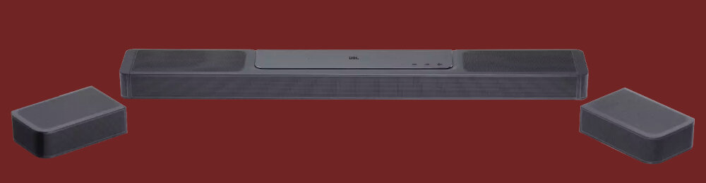 Na obrazie widoczny jest czarny soundbar z dwoma oddzielnymi głośnikami po bokach. Na górnej powierzchni soundbara znajdują się przyciski sterujące i logo producenta.