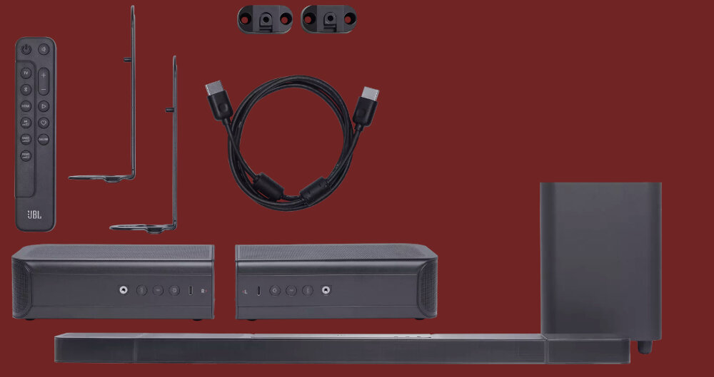 Na obrazie znajduje się zestaw soundbar z subwooferem, dwoma głośnikami, pilotem, uchwytami montażowymi i kablem HDMI. Logo \'JBL\' widoczne jest na pilocie.