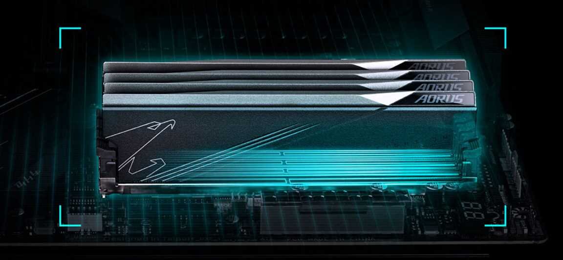 Na obrazie widoczna jest płyta główna z zamontowanymi modułami pamięci RAM, na których znajduje się logo AORUS. Tło jest ciemne z niebieskim podświetleniem.