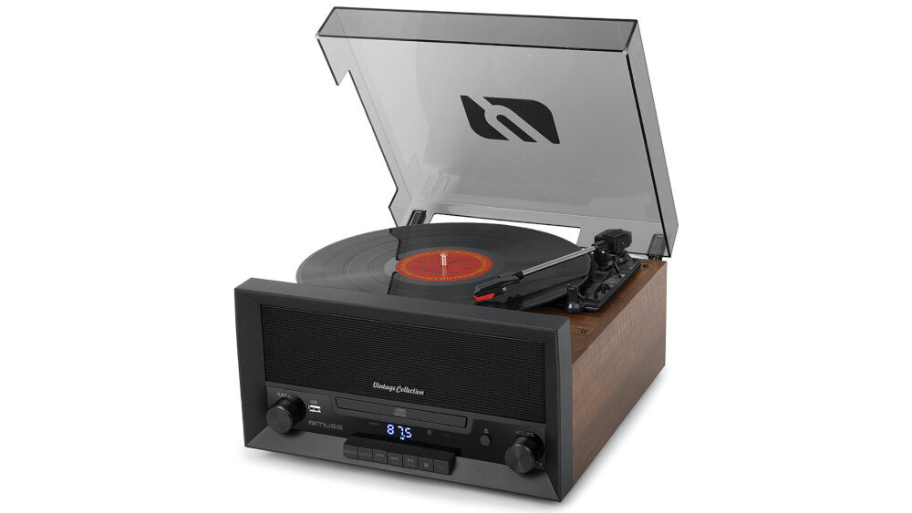 Gramofon z drewnianą obudową i przezroczystą pokrywą, na której widnieje logo. Na panelu przednim znajdują się pokrętła, wyświetlacz z niebieskim podświetleniem oraz przyciski sterujące.