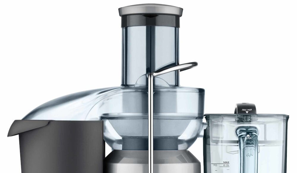 Na obrazie widoczna jest sokowirówka z metalicznymi i przezroczystymi elementami oraz pojemnik na sok z miarką. Produkt ma nowoczesny design i jest wykonany z metalu i tworzywa sztucznego.
