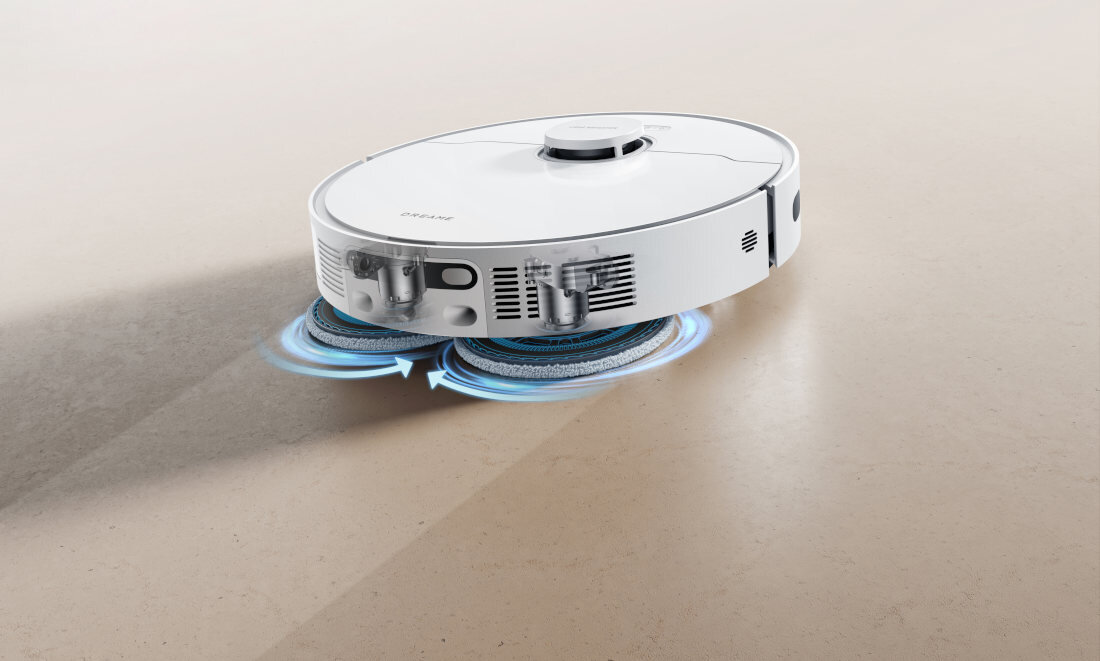Biały robot sprzątający z okrągłym korpusem i widocznymi szczotkami obracającymi się pod spodem. Na powierzchni robota znajduje się napis \'dreame\'.