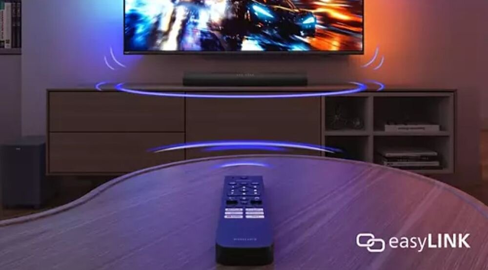Na obrazie widać telewizor z dynamiczną sceną oraz soundbar umieszczony poniżej. Na pierwszym planie znajduje się pilot, a w prawym dolnym rogu widnieje napis \'easyLINK\'.