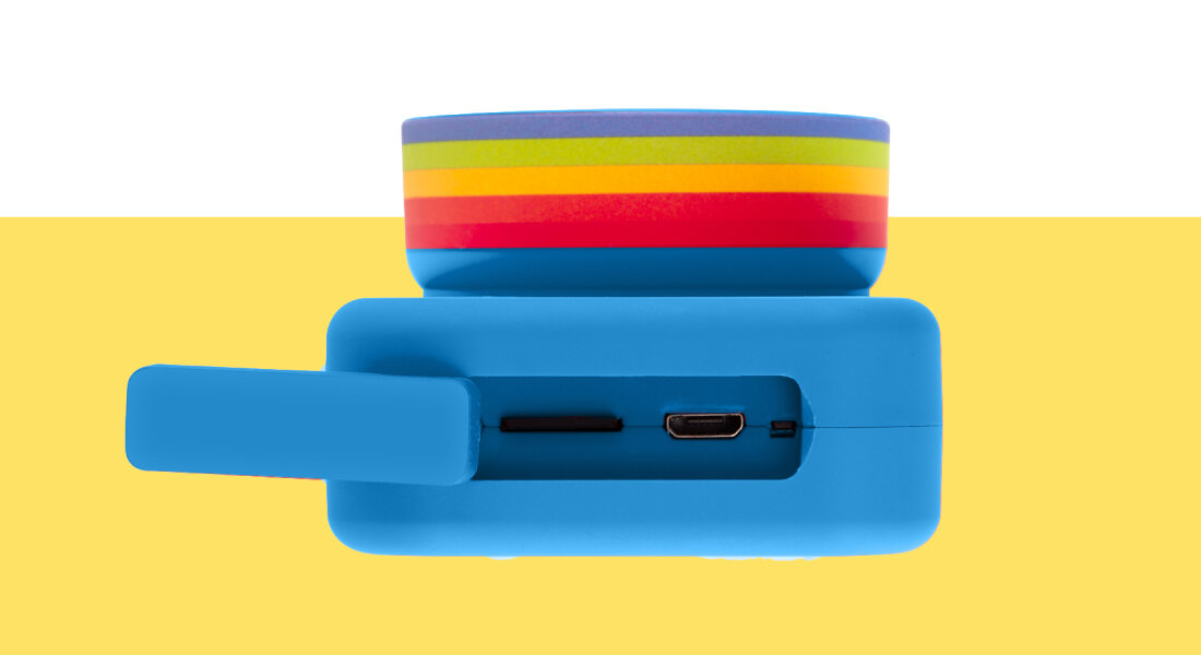 Niebieskie urządzenie z kolorowym paskiem na górze, posiada port USB i gniazdo na kartę pamięci. Tło jest żółto-białe.