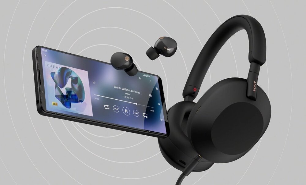 Na obrazie widoczny jest smartfon z wyświetlonym odtwarzaczem muzyki oraz czarne słuchawki nauszne i douszne z logo \'SONY\'.
