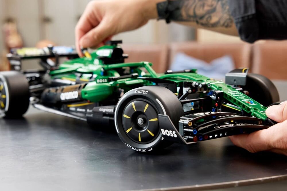 Osoba składa model zielonego bolidu wyścigowego z klocków LEGO, na którym widoczne są logotypy \'BOSS\' i \'Pirelli\'.