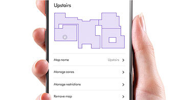 Osoba trzyma smartfon z aplikacją pokazującą mapę pomieszczeń z etykietą \'Upstairs\'. Widoczne opcje to \'Map name\', \'Manage zones\', \'Manage restrictions\', \'Remove map\'.