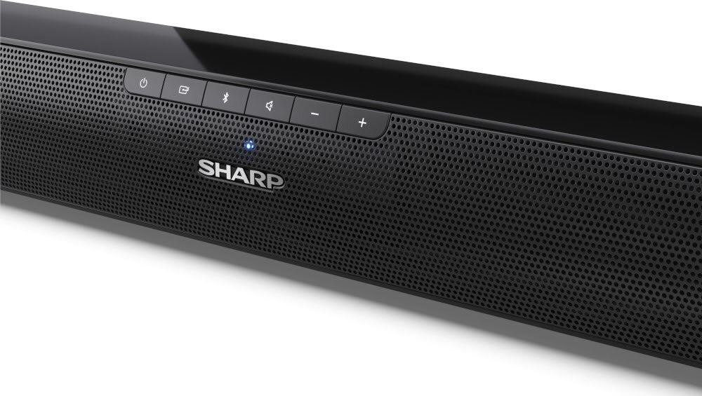 Czarny soundbar z widocznym logo SHARP i przyciskami sterującymi na górnej części urządzenia. Na panelu znajdują się ikony zasilania, wejścia, głośności i Bluetooth.