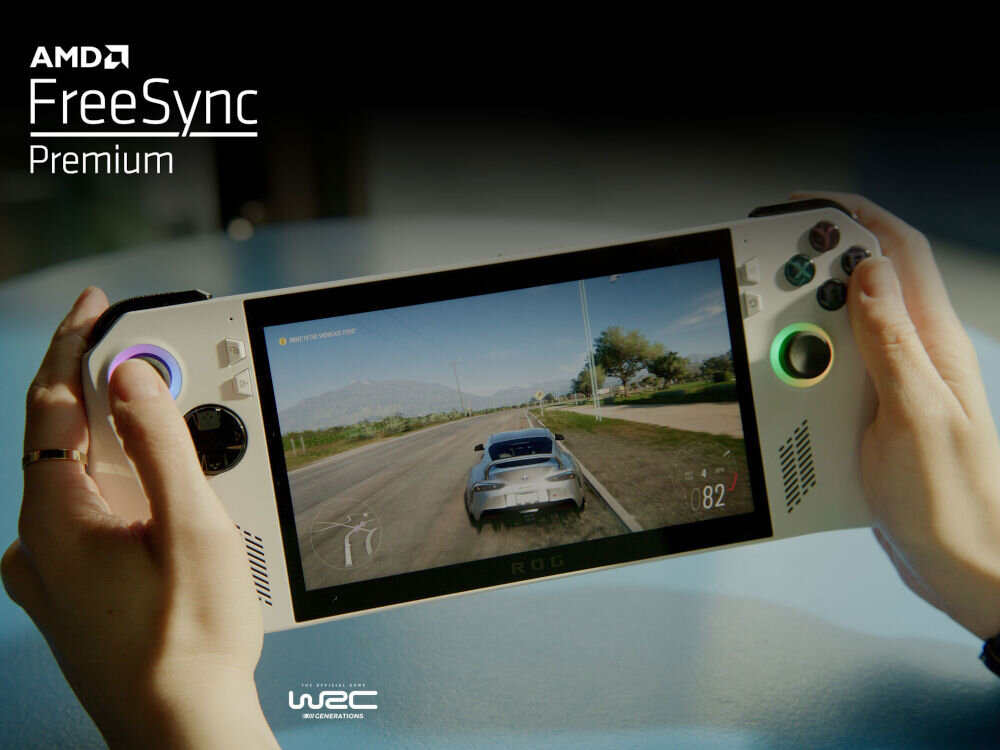 Osoba trzyma konsolę do gier z wyświetlaczem, na którym widać grę wyścigową. W lewym górnym rogu widoczny jest tekst \'AMD FreeSync Premium\'.