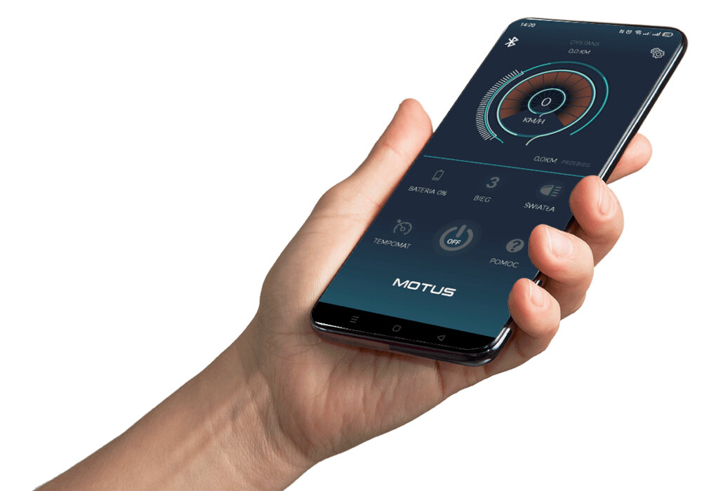 Osoba trzyma smartfon z aplikacją wyświetlającą prędkość i inne parametry. Na ekranie widoczny jest napis \'MOTUS\'.