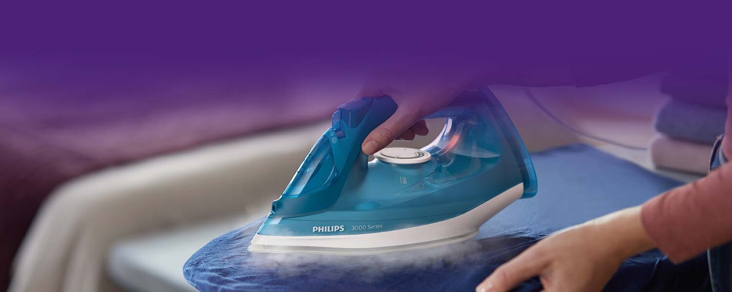 Osoba prasuje niebieski materiał za pomocą żelazka PHILIPS 3000 Series. Żelazko emituje parę podczas prasowania.