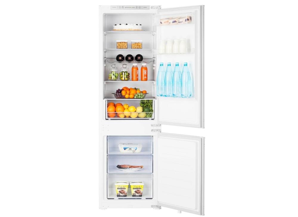 Otwarta lodówka z widocznymi półkami wypełnionymi różnorodnymi produktami spożywczymi, takimi jak owoce, napoje, nabiał i warzywa. Na drzwiach lodówki znajdują się butelki z wodą i kartony z mlekiem.