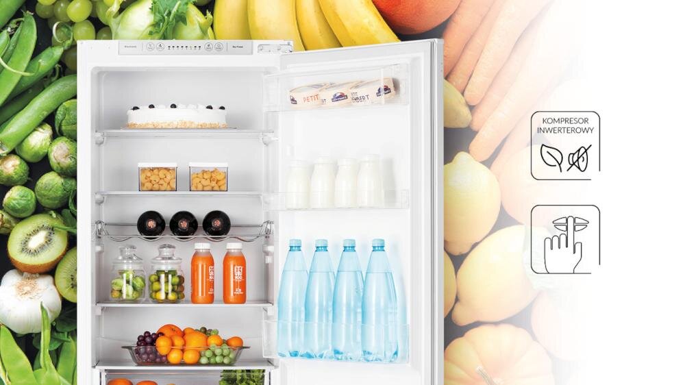 Otwarta lodówka z różnymi produktami spożywczymi, takimi jak ciasto, napoje, owoce i warzywa. Obok lodówki znajdują się ikony z napisami \'KOMPRESOR INWERTEROWY\'.