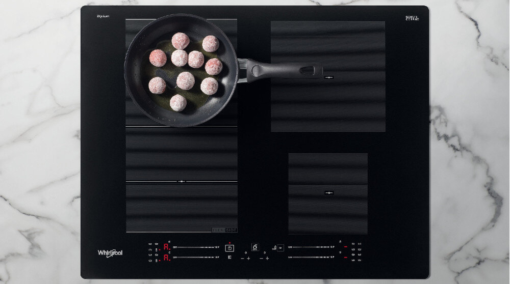 Czarna płyta indukcyjna z czterema strefami grzewczymi, na której znajduje się patelnia z kulkami. Widoczne logo: Whirlpool.