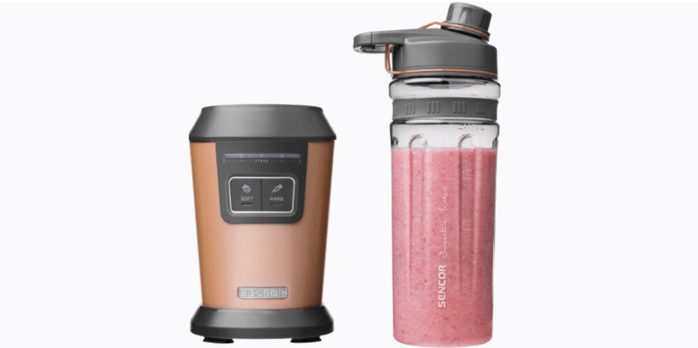 Na obrazie widoczny jest blender kielichowy w kolorze złotym z dwoma przyciskami na panelu oraz przezroczysty pojemnik z różowym napojem. Na pojemniku znajduje się napis \'SENCOR\'.