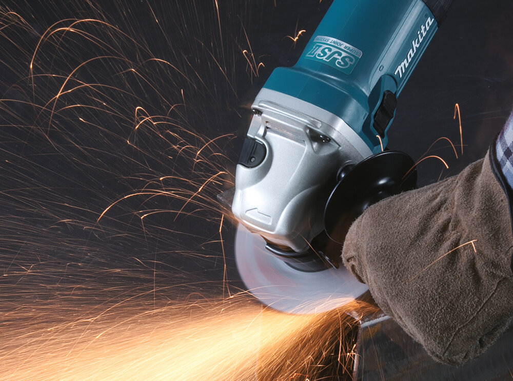 Szlifierka kątowa MAKITA GA5040C zbliżenie na szlifierkę osoba szlifuje metalowy element iskry spod tarczy wszechstronne narzędzie wysoka wydajność regulacja prędkości wygodna obsługa