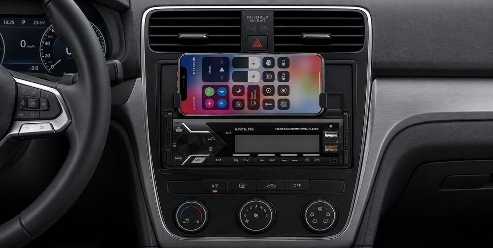 Wnętrze samochodu z zamontowanym radiem NAVITEL RD6 Bluetooth Pilot. Na radiu znajduje się uchwyt z telefonem, na którym widoczny jest ekran z ikonami aplikacji.