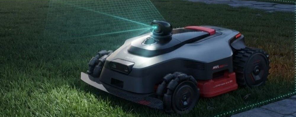 Robot koszący na trawie z widocznym systemem nawigacji laserowej. Urządzenie ma ciemnoszary korpus z czerwonymi akcentami i dużymi kołami.