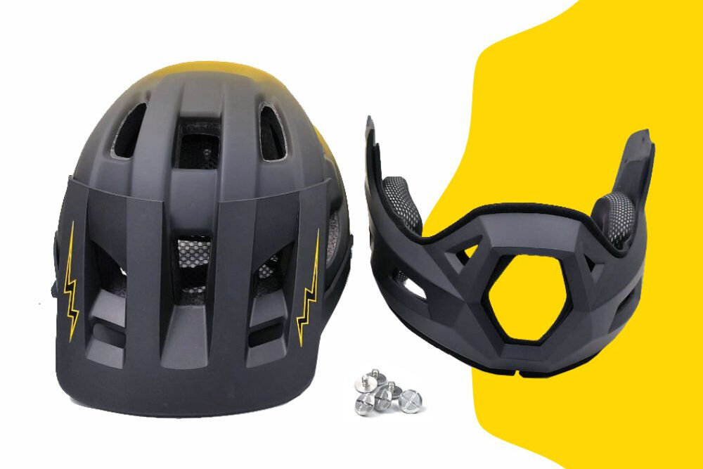 Czarno-żółty kask rowerowy z odkręcaną szczęką, widoczny z tyłu z żółtymi wzorami w kształcie błyskawic. Obok znajduje się odkręcona część szczęki oraz kilka srebrnych śrubek.