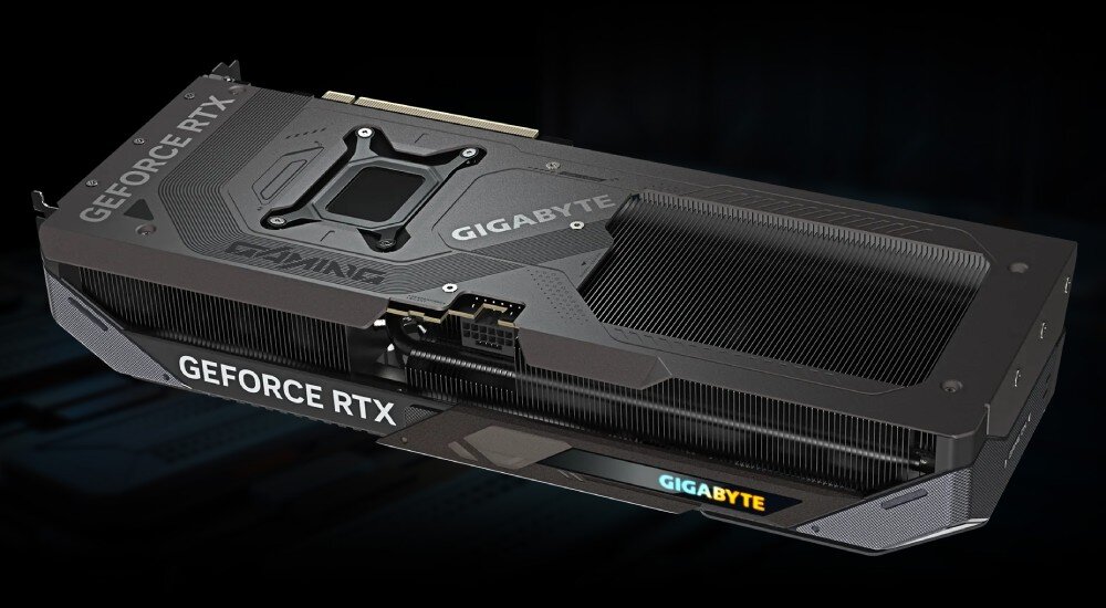 Na obrazie widoczna jest karta graficzna z napisami \'GIGABYTE\', \'GAMING\' i \'GEFORCE RTX\'. Karta ma ciemną obudowę z metalicznymi elementami i widocznymi radiatorami.