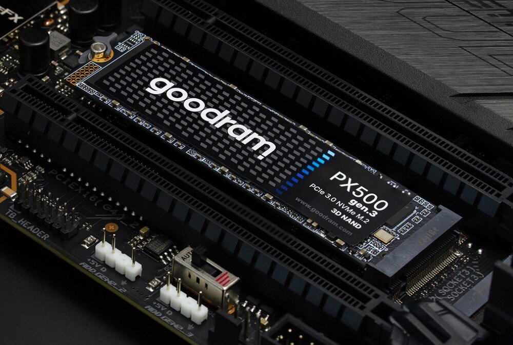Na obrazie widoczny jest dysk SSD z napisem \'goodram PX500 PCIe 3.0 NVMe M.2 3D NAND\' zamontowany na płycie głównej. W tle znajdują się elementy elektroniczne i złącza płyty głównej.