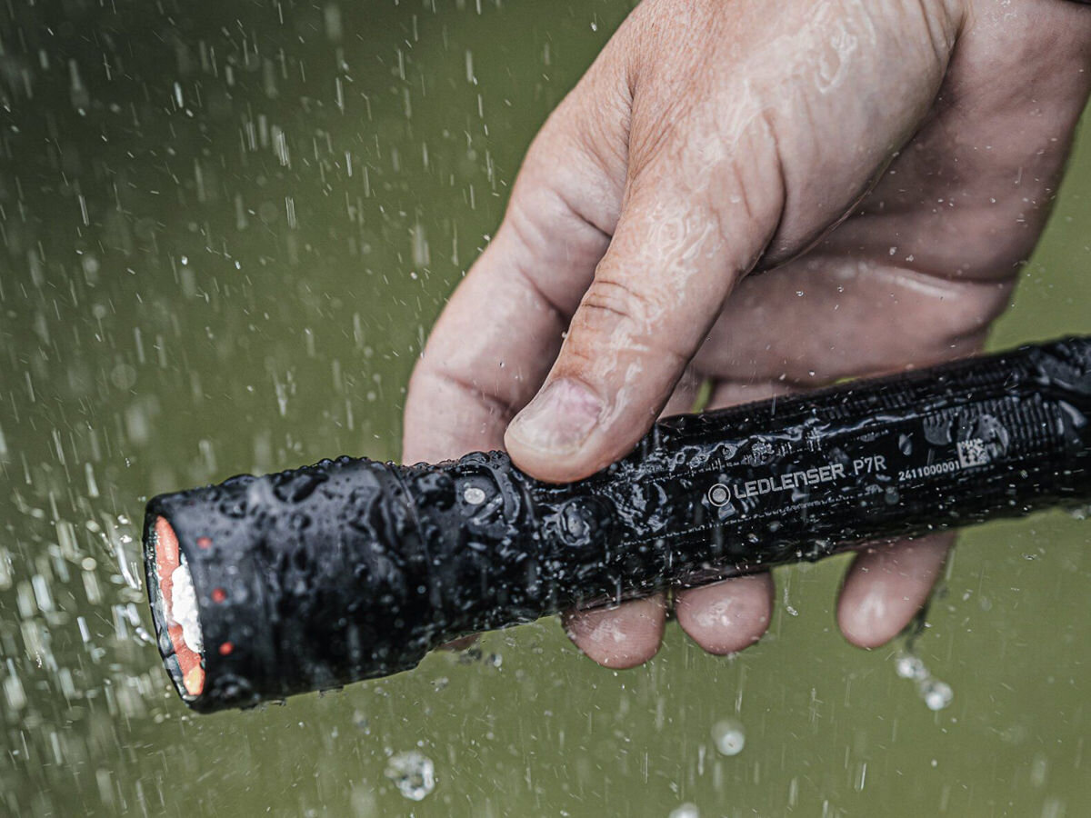 Latarka LEDLENSER P7R, aluminium, odpornośc, uszkodzenia, utwardzane, dłoń trzyma latarkę w porze deszczowej