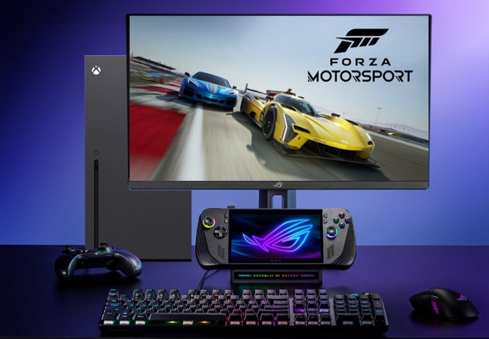 Na obrazie widoczny jest monitor z wyświetlaną grą \'Forza Motorsport\', obok którego znajduje się konsola, kontroler, klawiatura i mysz. Na ekranie monitora widać dwa samochody wyścigowe, a poniżej znajduje się urządzenie z logo ROG.